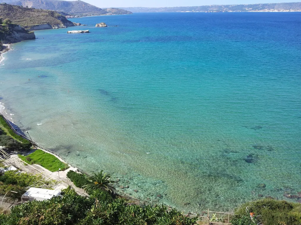 The crescent-shaped sandy beach and calm turquoise waters of Kera beach in Crete, Greece.